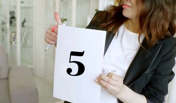 женщина держит лист бумаги с цифрой 5